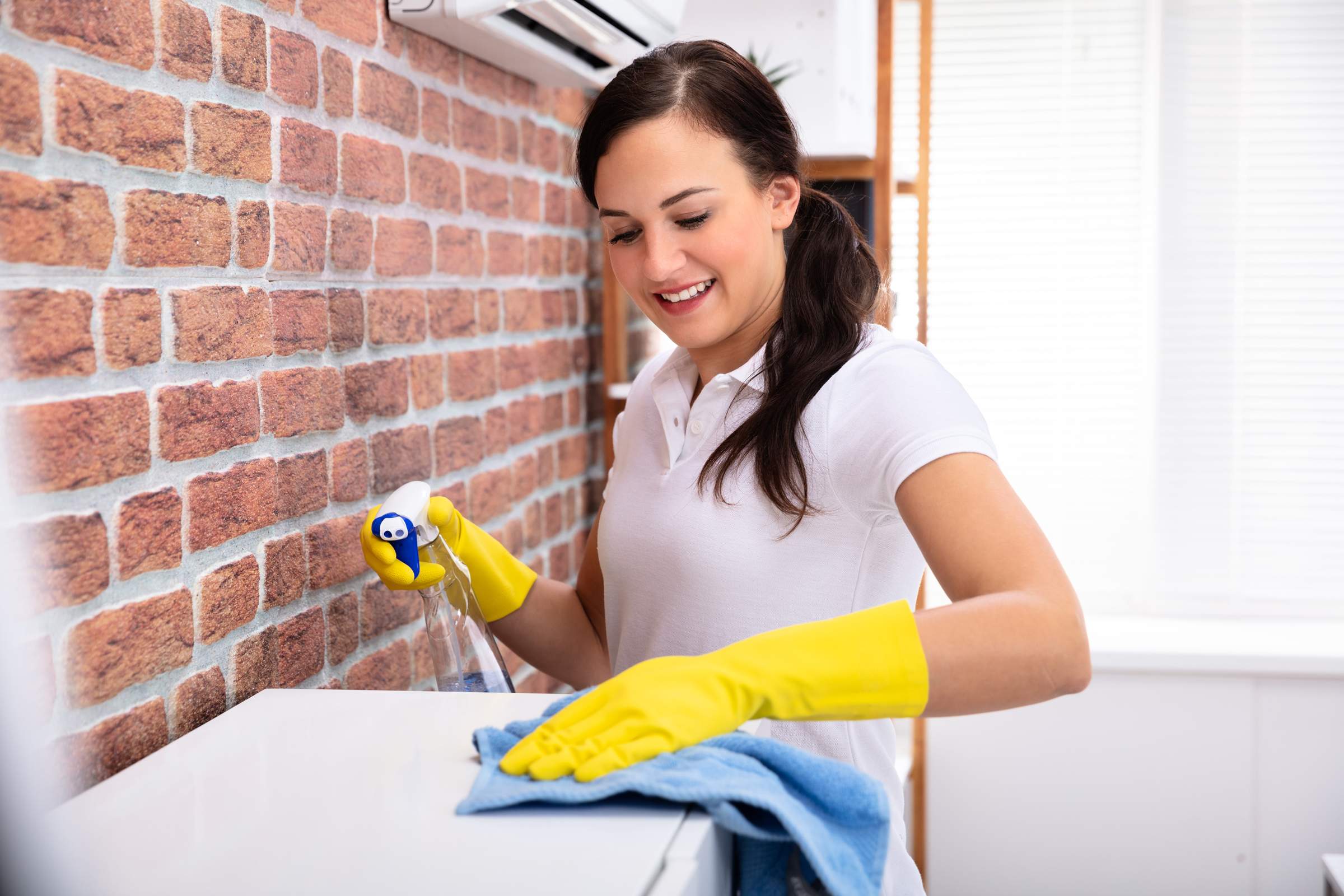 house cleaner wiping top of cabinet